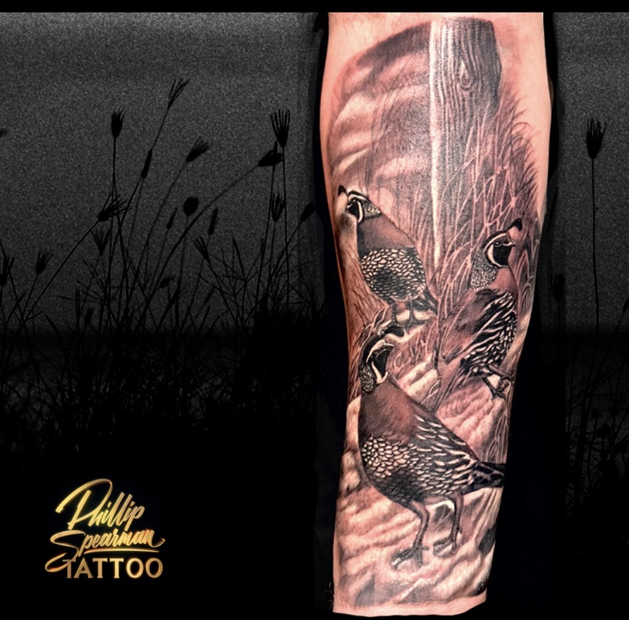 This black and grey arm panel beautifully captures three quails, each representing a sibling, nestled together near a weathered post. The intricate feather textures and varied markings on each bird are brought to life through precise shading, creating a sense of quiet naturalism within the composition.