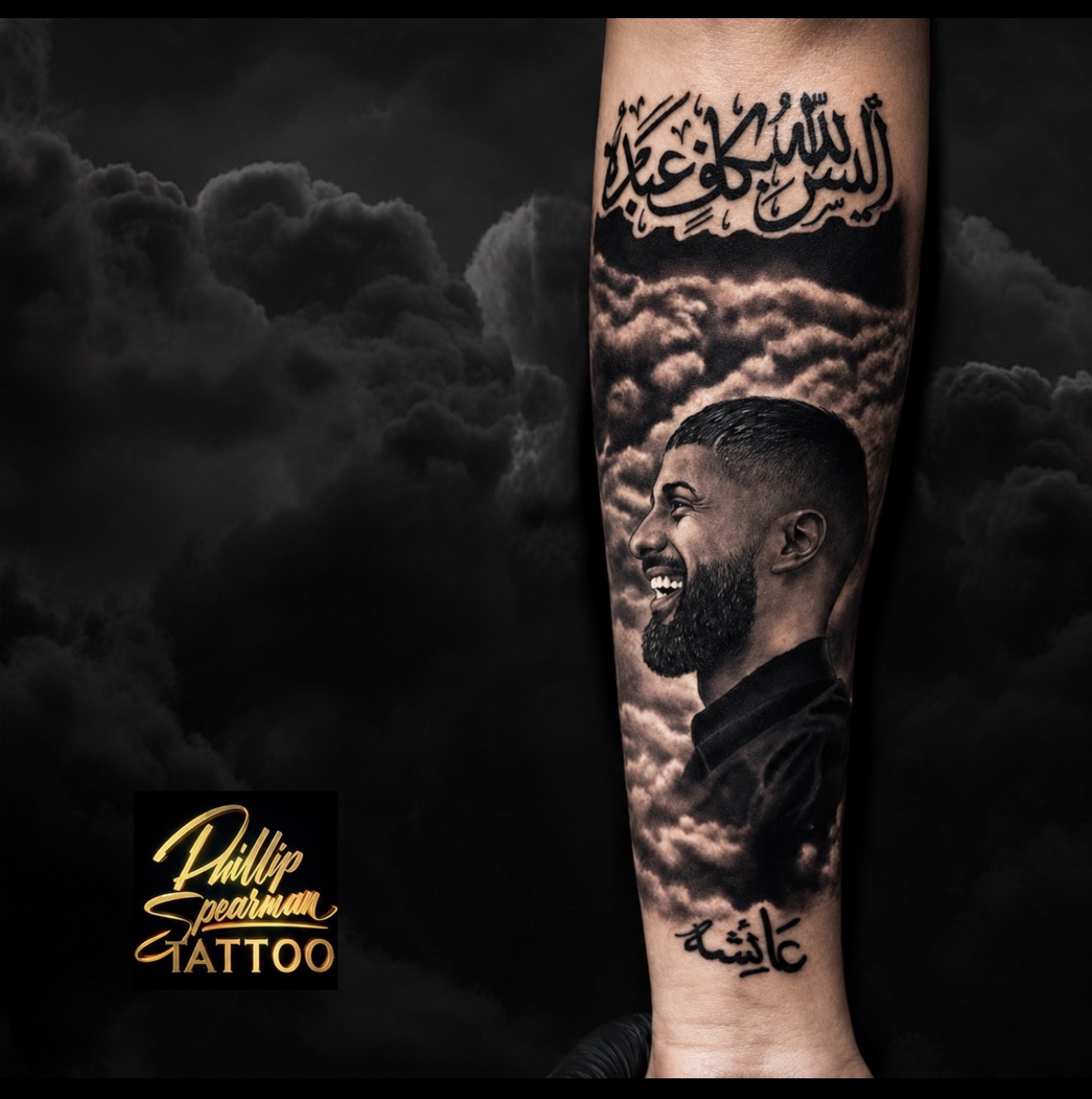 This forearm portrait beautifully captures the love for a brother, rendered with a radiant smile amidst soft, billowing clouds. The intricate Arabic calligraphy above grounds the piece, complemented by a delicate inscription near the wrist, all in a compelling black and grey palette. Every detail, from the textured beard to the atmospheric depth of the clouds, contributes to a deeply personal and striking tribute.