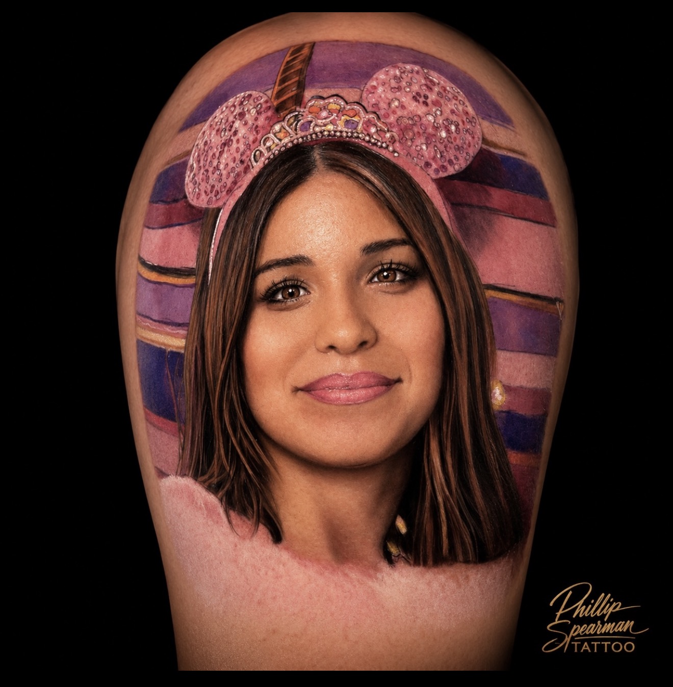 This vibrant portrait beautifully captures a cherished family memory on the skin. Phillip masterfully rendered the intricate sparkle of the Minnie ears and crown, bringing a joyful spirit to life. The expressive eyes and subtle gradients in the background create a vivid narrative, reflecting a truly special bond.